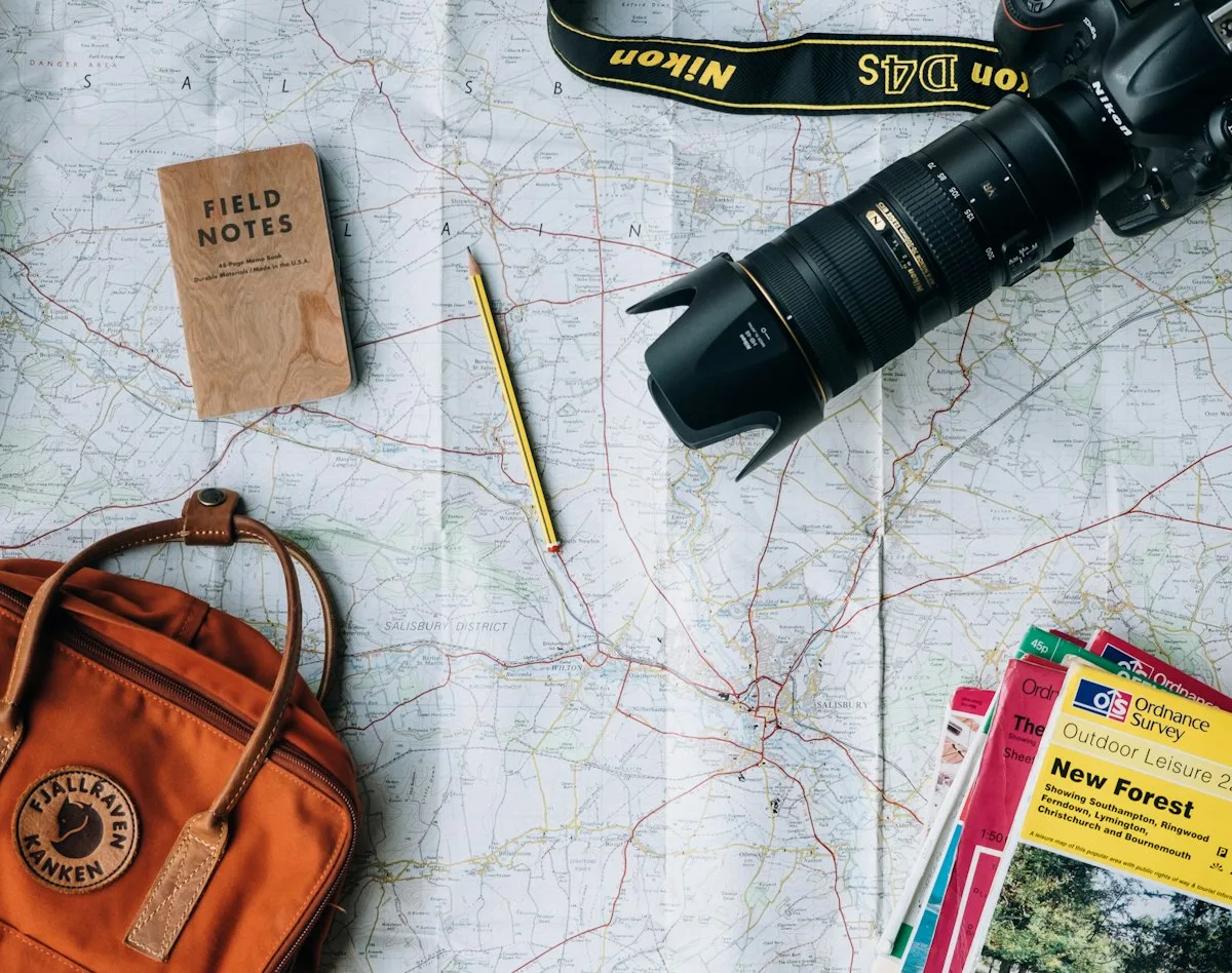 A map, camera and notebook arranged for travel planning