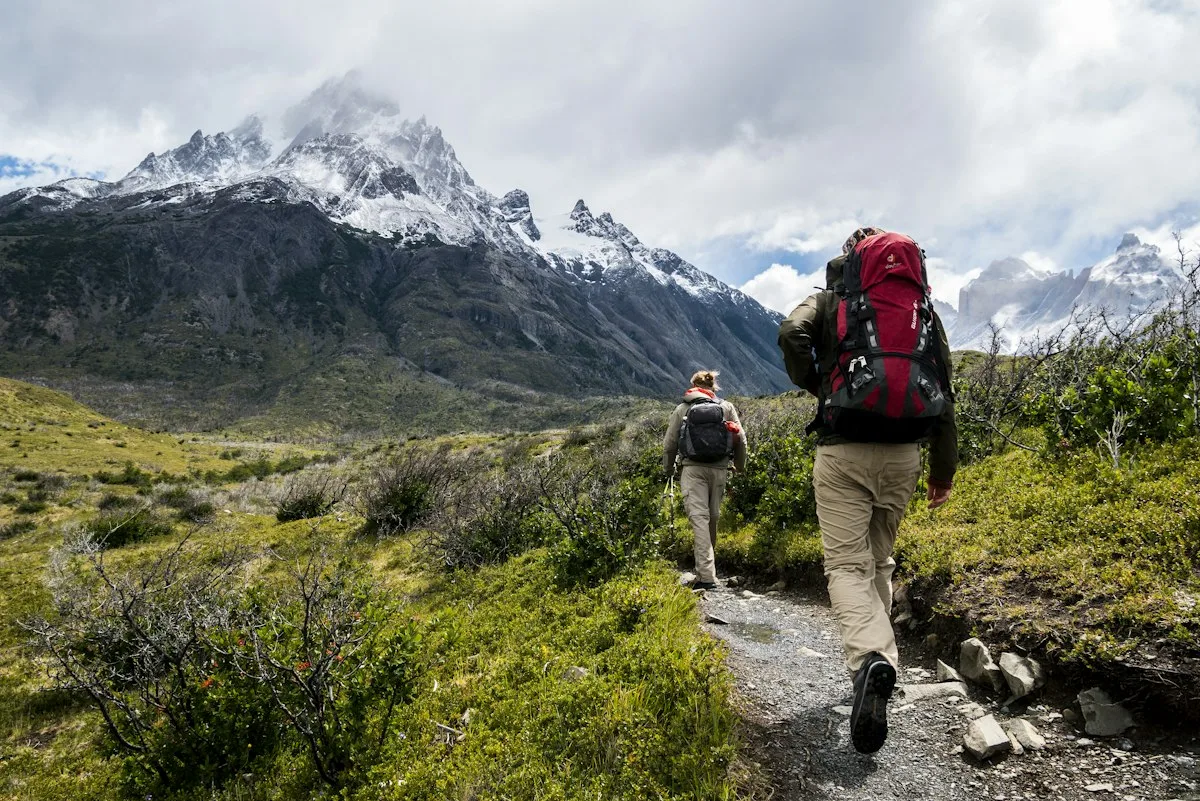 Travelers hiking with backpacks below snowy mountains