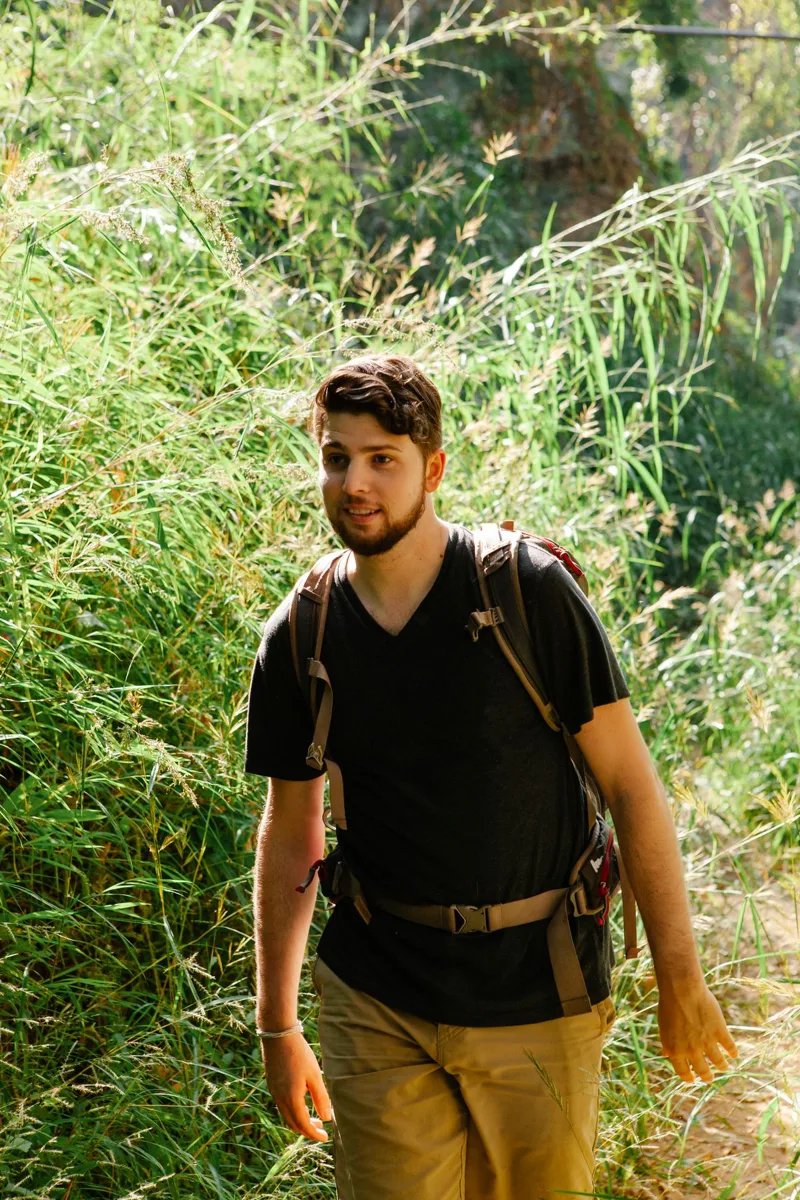 A traveler walking on a woodland path with a backpack
